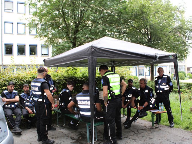Sicherheitsmitarbeiter von CMS sitzen unter einem Pavillon während einer Pause beim Seehasenfest 2024 in Friedrichshafen.