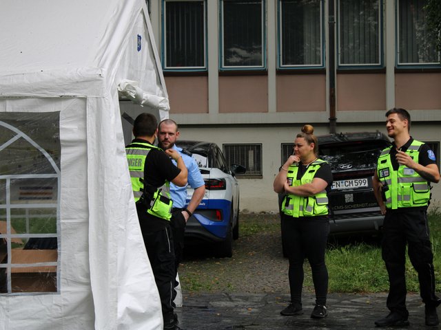 Sicherheitskräfte unterhalten sich und bereiten sich auf ihre Aufgaben beim Seehasenfest 2024 in Friedrichshafen vor.