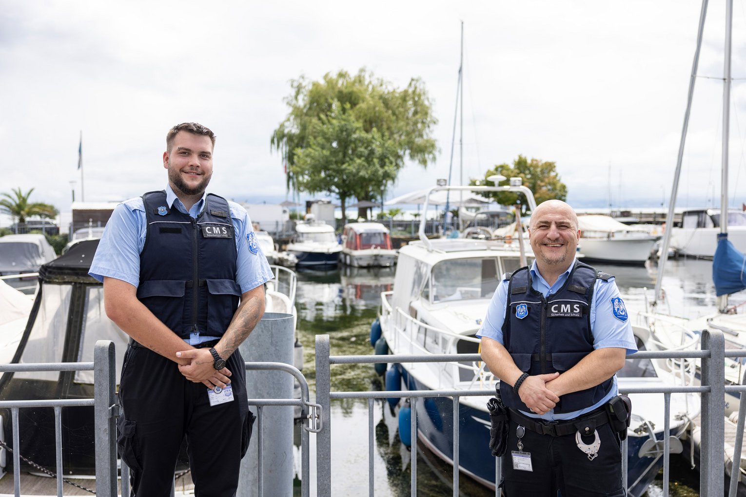Zwei Mitarbeiter von CMS-Sicherheit stehen am Hafen vor Booten