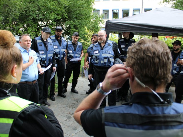 Sicherheitsmitarbeiter hören einem Briefing ihres Teamleiters beim Seehasenfest 2024 in Friedrichshafen zu.
