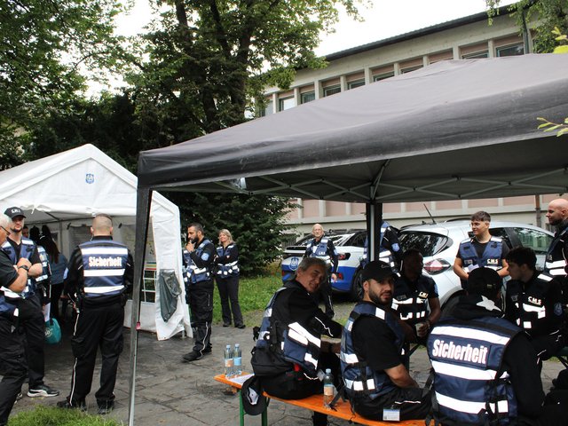 Sicherheitskräfte unterhalten sich und ruhen sich unter einem Pavillon während des Seehasenfests 2024 in Friedrichshafen aus.