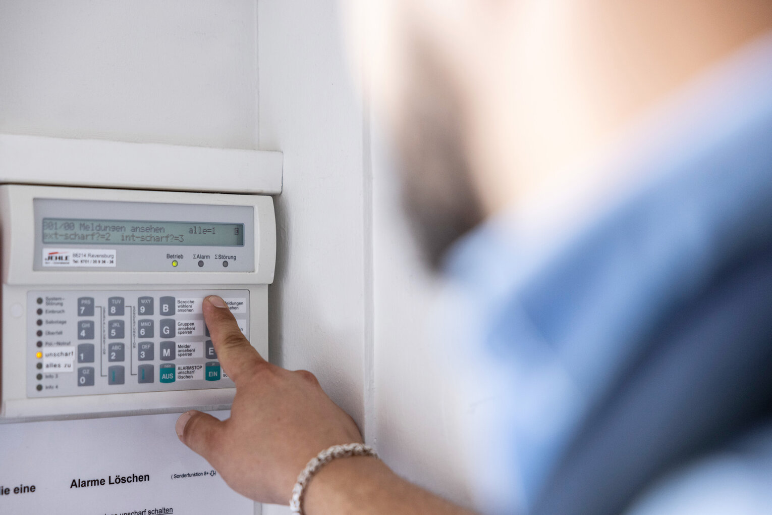 Nahaufnahme eines Sicherheitsmitarbeiters von CMS-Sicherheit, der eine Alarmanlage bedien